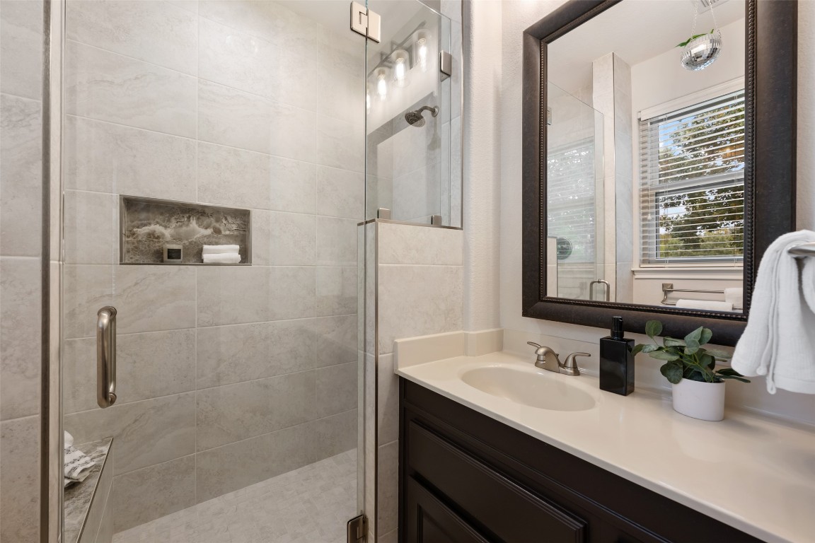 6020 Rutledge Lane Austin, TX 78745 - Photo 7 of 40 a bathroom with a granite countertop sink a mirror a potted plant and a shower