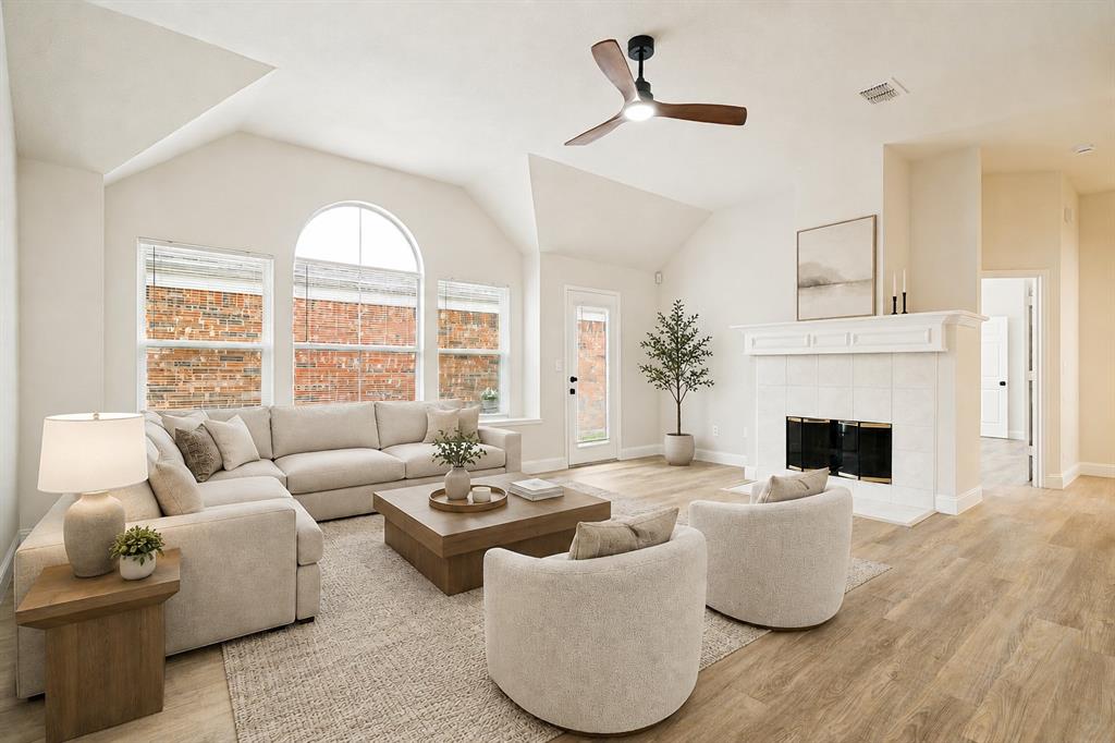 3020 Ridge Hollow Drive Plano, TX 75023 - Photo 4 of 28 Vaulted living room featuring wood-finish flooring, a white tile fireplace with a detailed mantel, and multiple windows including an arched transom