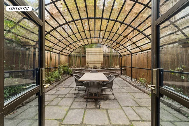 a patio with table and chairs and potted plants