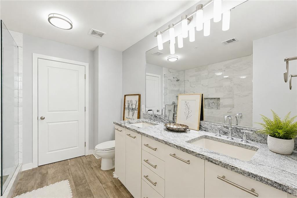 3300 Windy Ridge Parkway Southeast, Unit 1112 Atlanta, GA 30339 - Photo 18 of 43 a bathroom with a granite countertop sink a toilet and a mirror