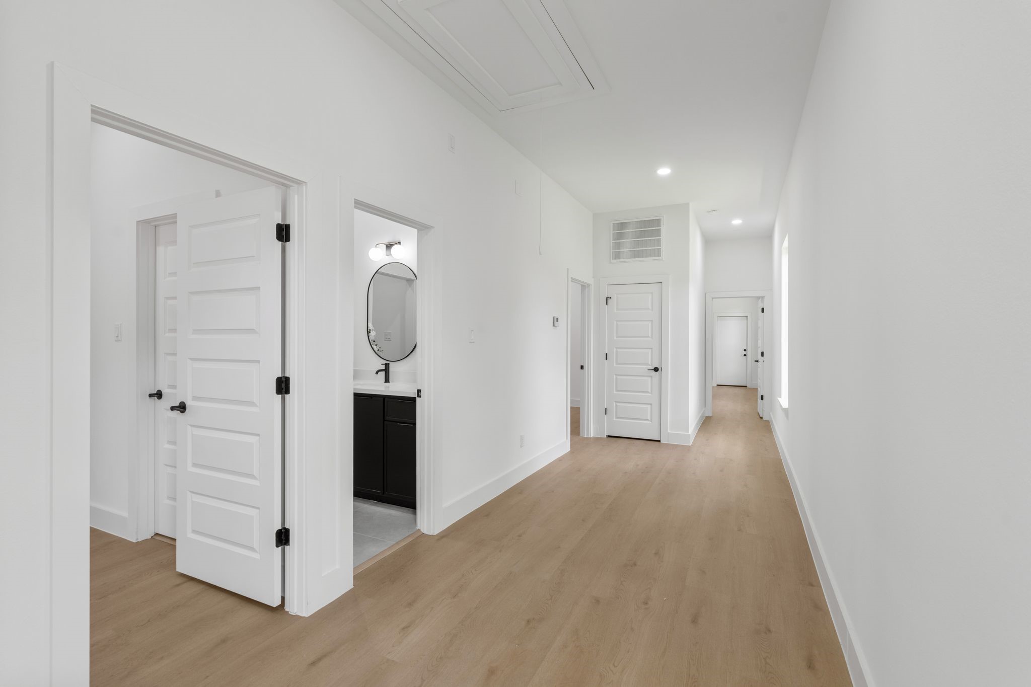 7321 Laura Koppe Road Houston, TX 77028 - Photo 13 of 41 Bright, spacious hallway with elegant wood flooring, modern light fixtures, and crisp white walls leading to multiple rooms, including a stylish bathroom.