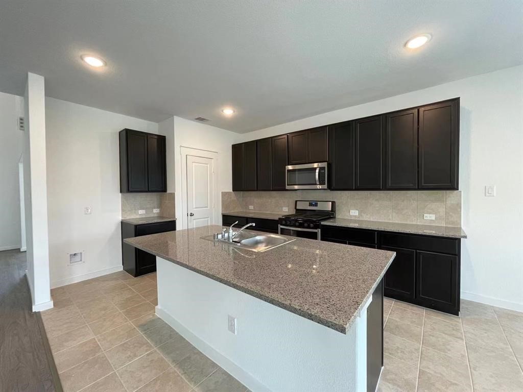 815 Summer Village Way Rosenberg, TX 77469 - Photo 5 of 21 a kitchen with a stove top oven a sink dishwasher a refrigerator and a microwave