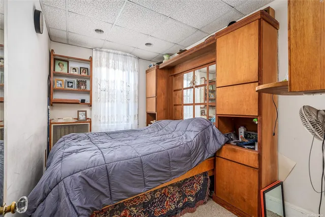 a bedroom with a bed a dresser and a large window