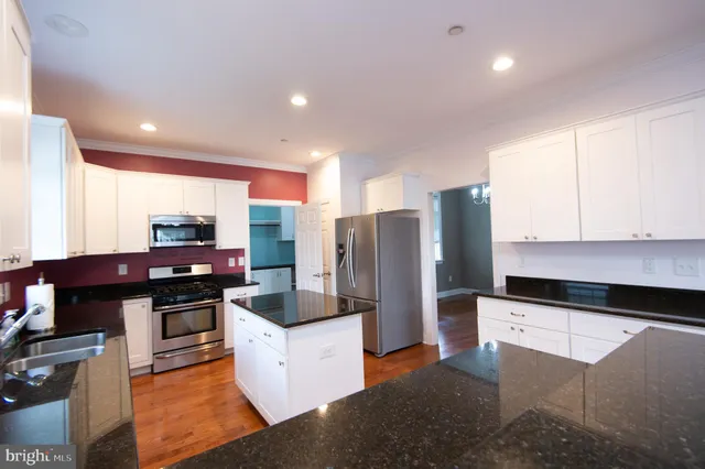 a kitchen with granite countertop white cabinets and a wooden floor