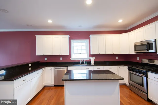 a kitchen with granite countertop a sink a stove and cabinets