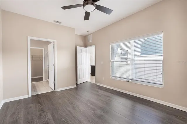a view of an empty room with a window and wooden floor