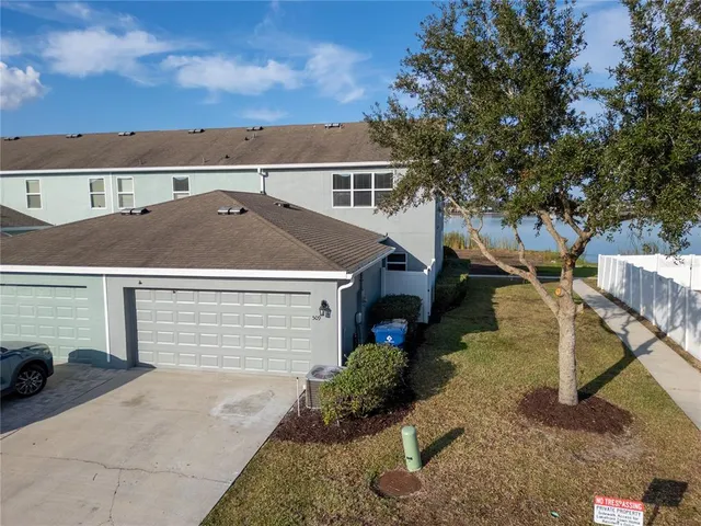 a view of a house with a small yard and a large tree