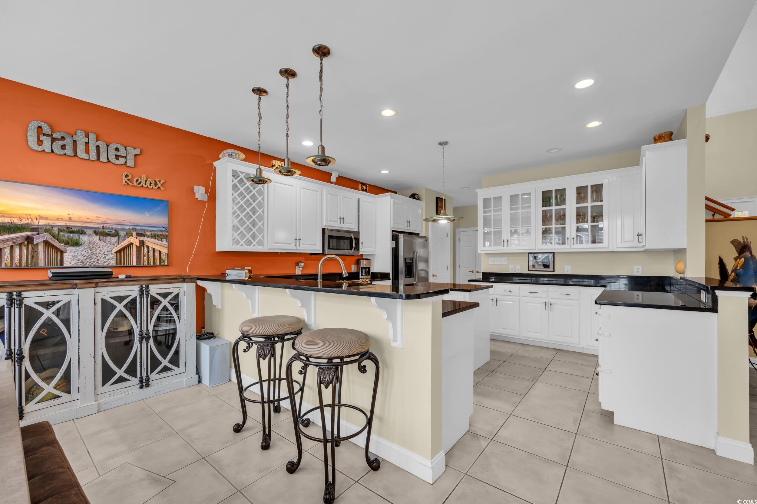 830 Channel Cat Cove Murrells Inlet, SC 29576 - Photo 12 of 40 Kitchen with white cabinetry, a breakfast bar area, hanging light fixtures, stainless steel appliances, and a center island with sink