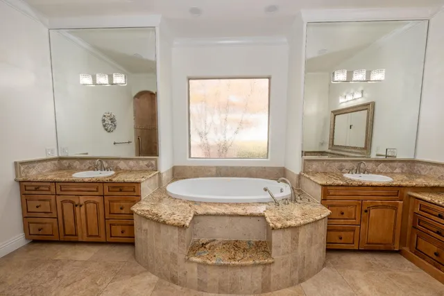 a bathroom with a granite countertop tub a double vanity sink and a large mirror