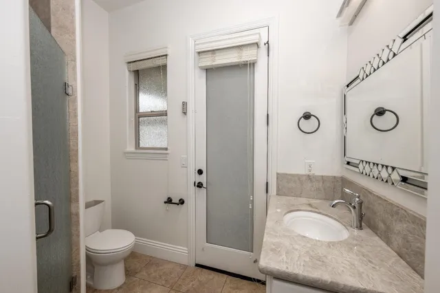 a bathroom with a granite countertop sink toilet and a mirror