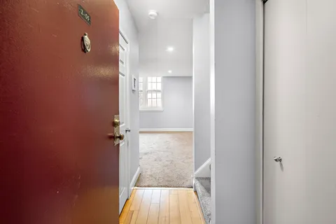 a view of a hallway with wooden floor and a bathroom