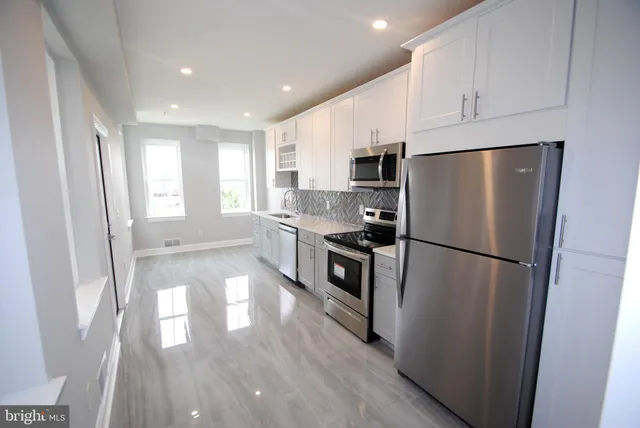 a kitchen with stainless steel appliances a refrigerator a sink a stove a microwave a center island and cabinets