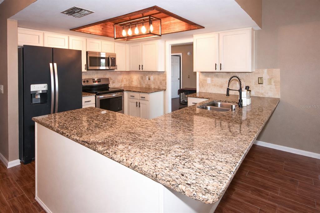 13277 Delbarton Street Spring Hill, FL 34609 - Photo 6 of 22 a kitchen with stainless steel appliances granite countertop a sink refrigerator and microwave