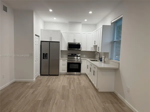 a kitchen with granite countertop a refrigerator oven a sink dishwasher and wooden floor