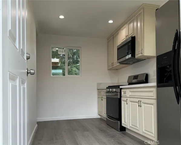 a kitchen with stainless steel appliances granite countertop white cabinets a sink a stove a refrigerator and a microwave