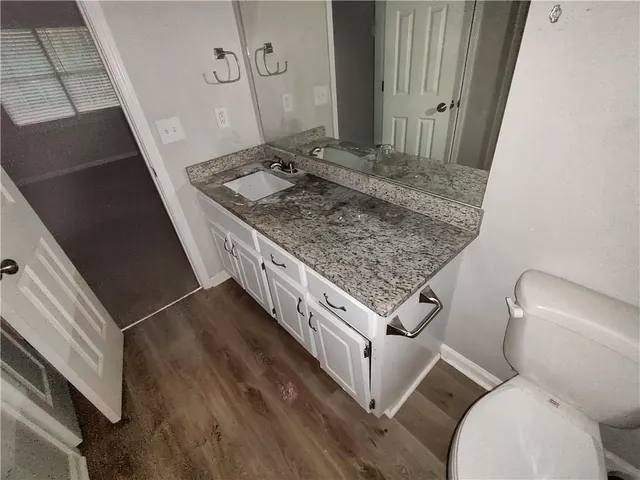 a bathroom with a granite countertop sink and a toilet