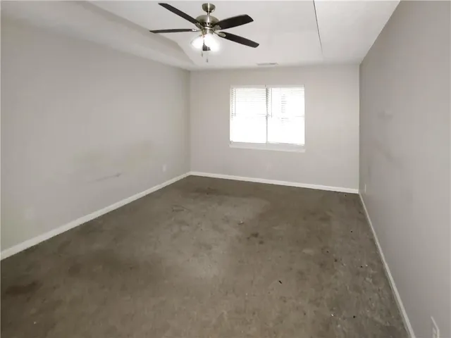 an empty room with a window and a fan