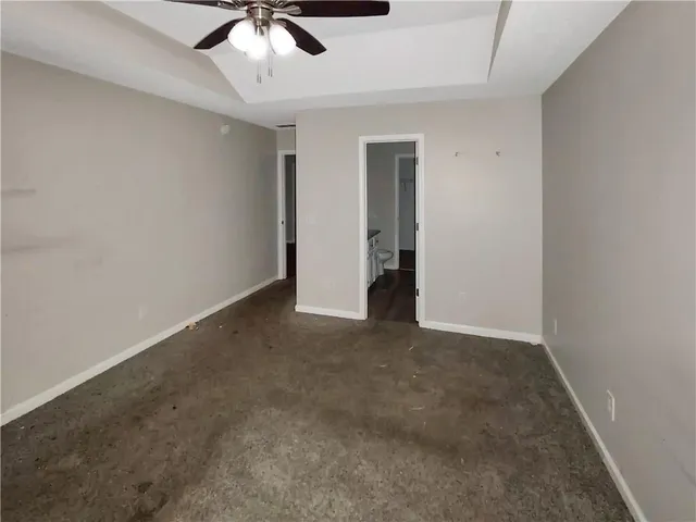 an empty room with chandelier fan and windows