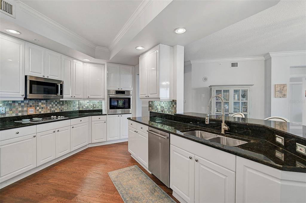 385 North Point Road, Unit 402 Osprey, FL 34229 - Photo 11 of 62 a kitchen with granite countertop a sink and white cabinets