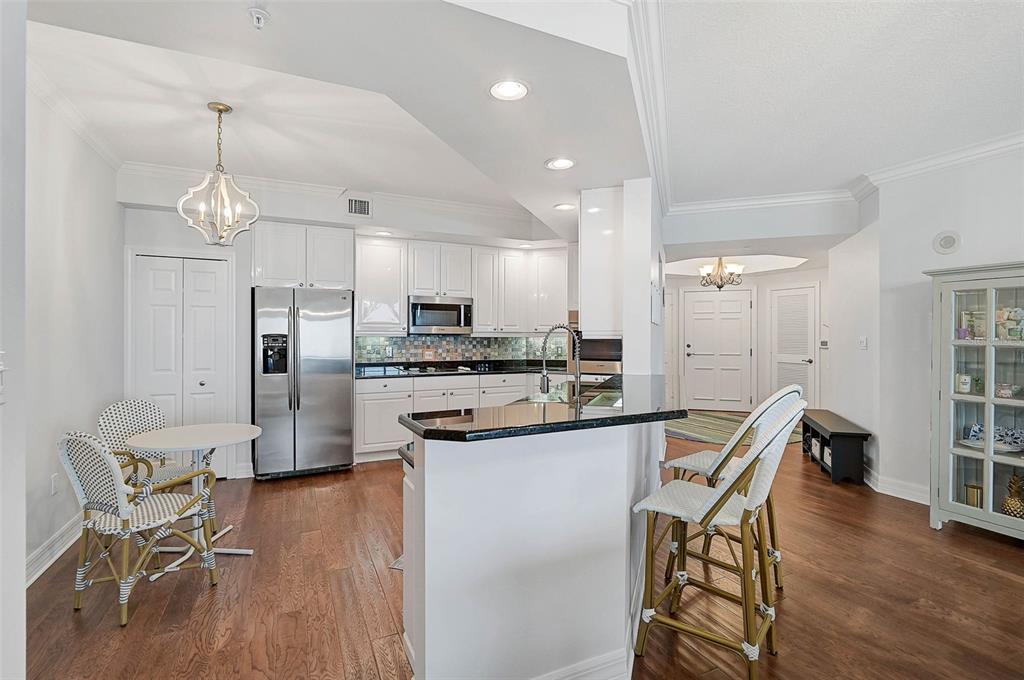 385 North Point Road, Unit 402 Osprey, FL 34229 - Photo 10 of 62 a kitchen with stainless steel appliances kitchen island granite countertop a dining table chairs and granite counter tops