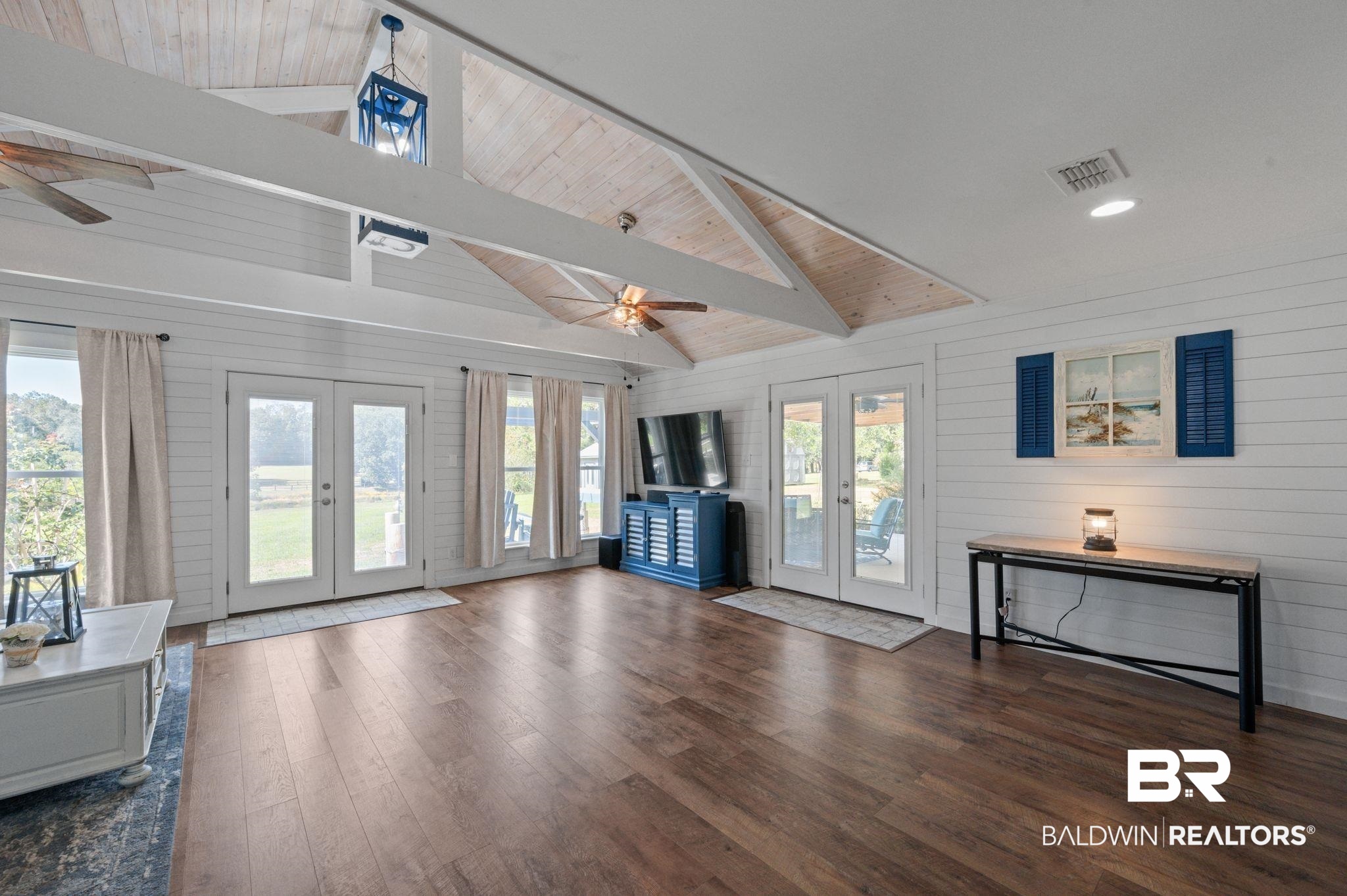 20037 County Road 33 Fairhope, AL 36532 - Photo 9 of 79 Living room with vaulted ceiling with beams, french doors, dark hardwood / wood-style flooring, ceiling fan, and wooden walls