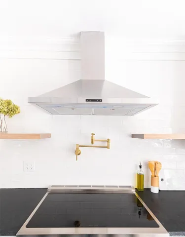 a kitchen with stainless steel appliances kitchen island granite countertop a sink a stove a refrigerator and white cabinets with wooden floor