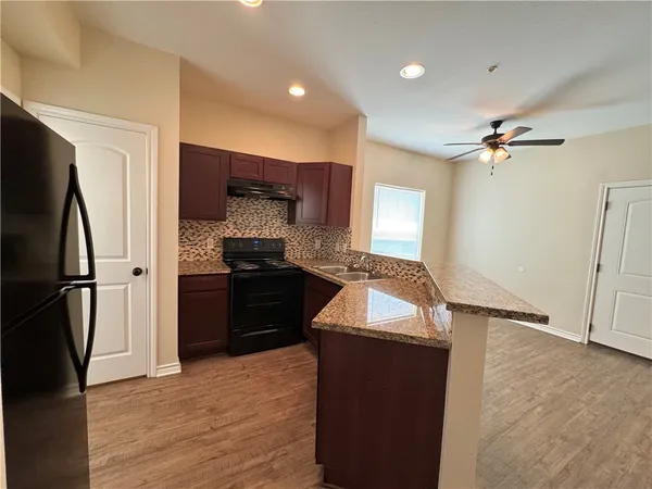 a kitchen with granite countertop a refrigerator stove and sink