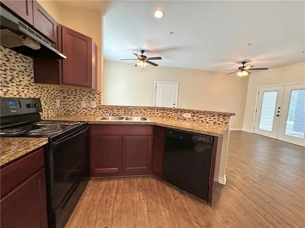 a kitchen with granite countertop a stove cabinets and wooden floor