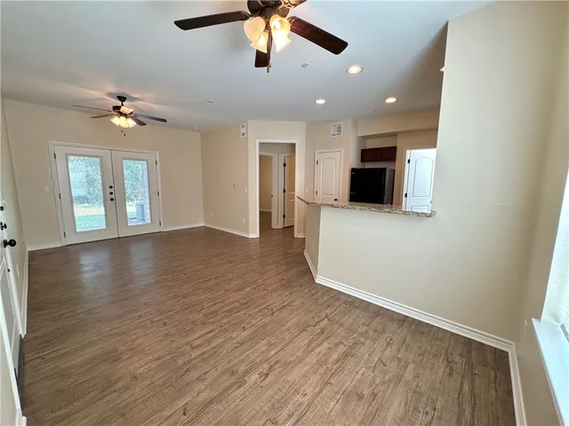an empty room with wooden floor ceiling fan and windows