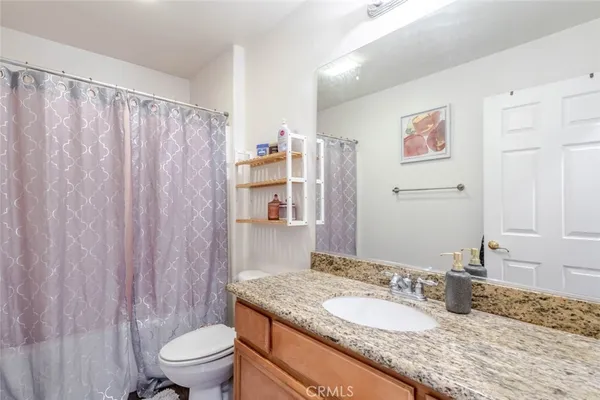 a bathroom with a granite countertop sink mirror vanity and toilet