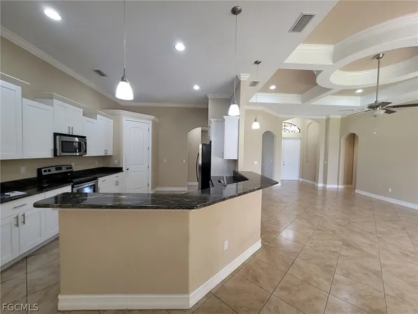 a large kitchen with granite countertop a large counter top stainless steel appliances and cabinets