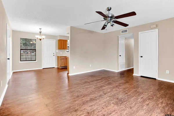 a view of empty room with wooden floor and ceiling fan