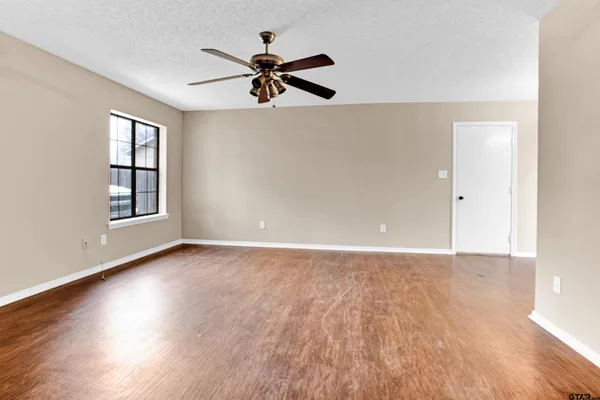 a view of an empty room with wooden floor and a window