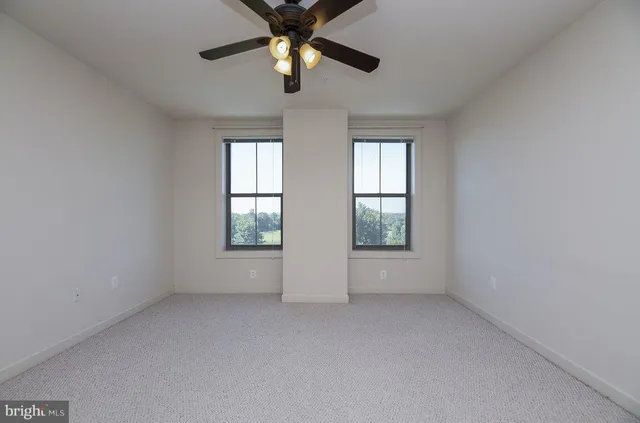 an empty room with windows and chandelier fan