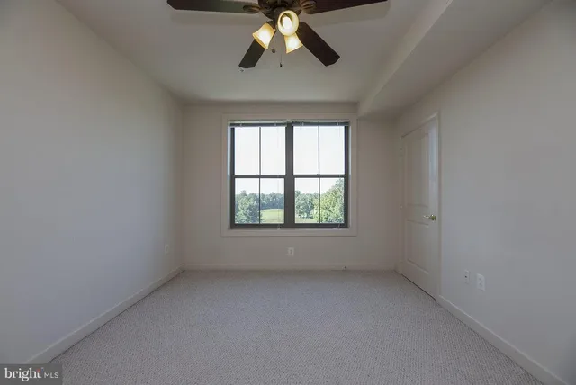 an empty room with a chandelier fan and windows