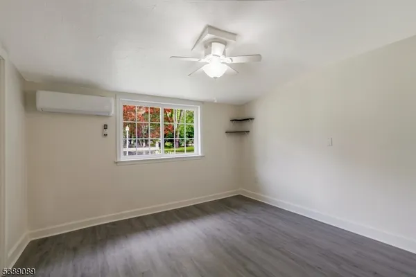 an empty room with wooden floor chandelier fan and windows