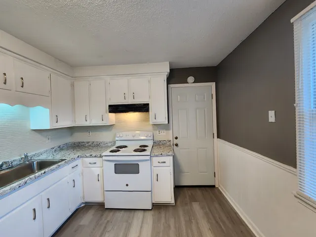 a kitchen with cabinets appliances and wooden floor
