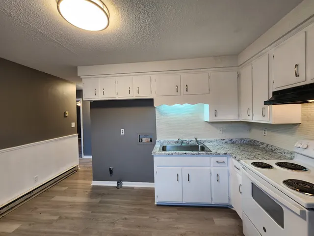 a kitchen with granite countertop white cabinets and white appliances