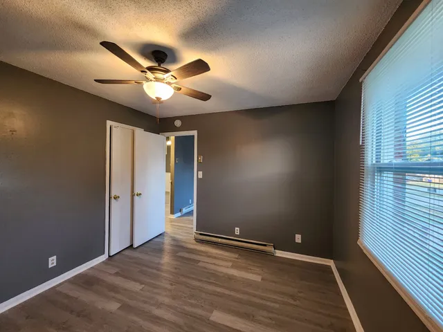 a view of an empty room with wooden floor and a window