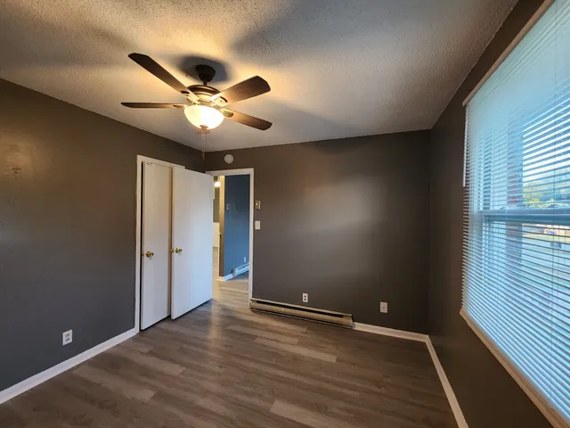 a view of an empty room with wooden floor and a window
