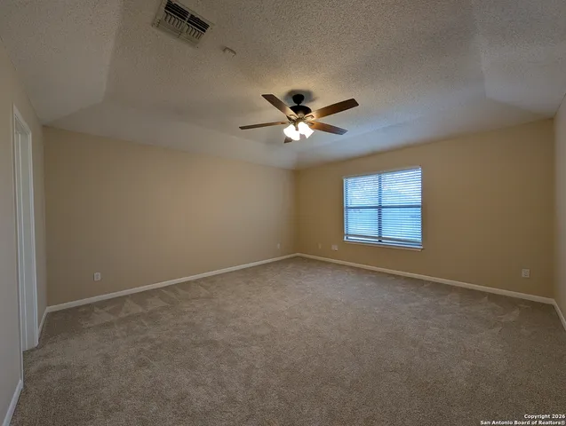 an empty room with windows and ceiling fan