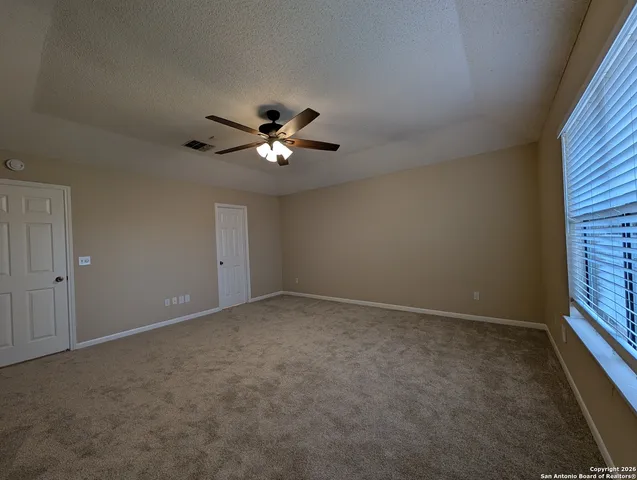 an empty room with windows and fan