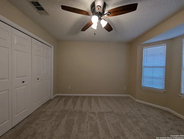 an empty room with a window and a fan