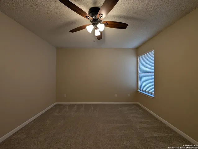 an empty room with windows and fan