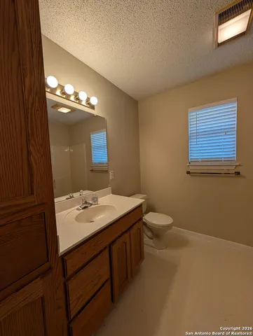 a bathroom with a granite countertop sink a toilet and a mirror