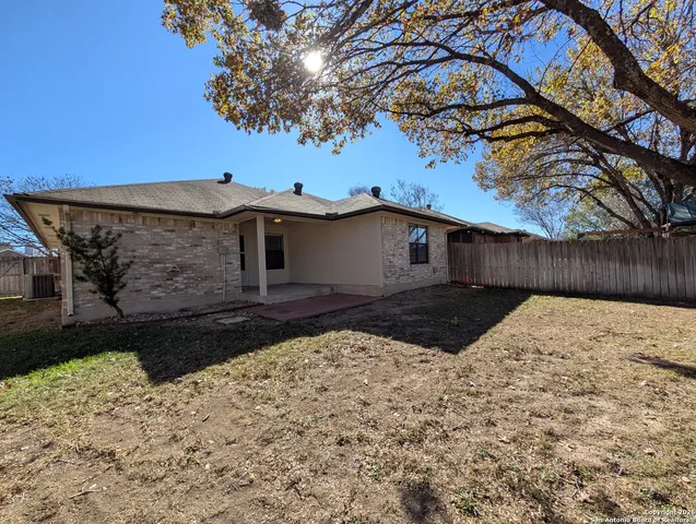 a view of a house with a yard tree and a wooden fence
