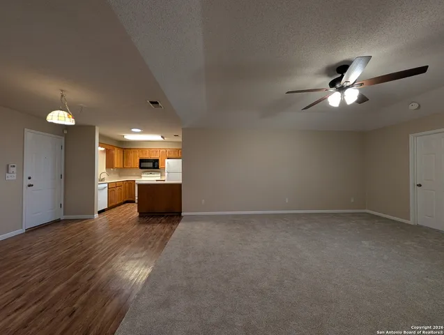 a view of a big room with wooden floor and a kitchen