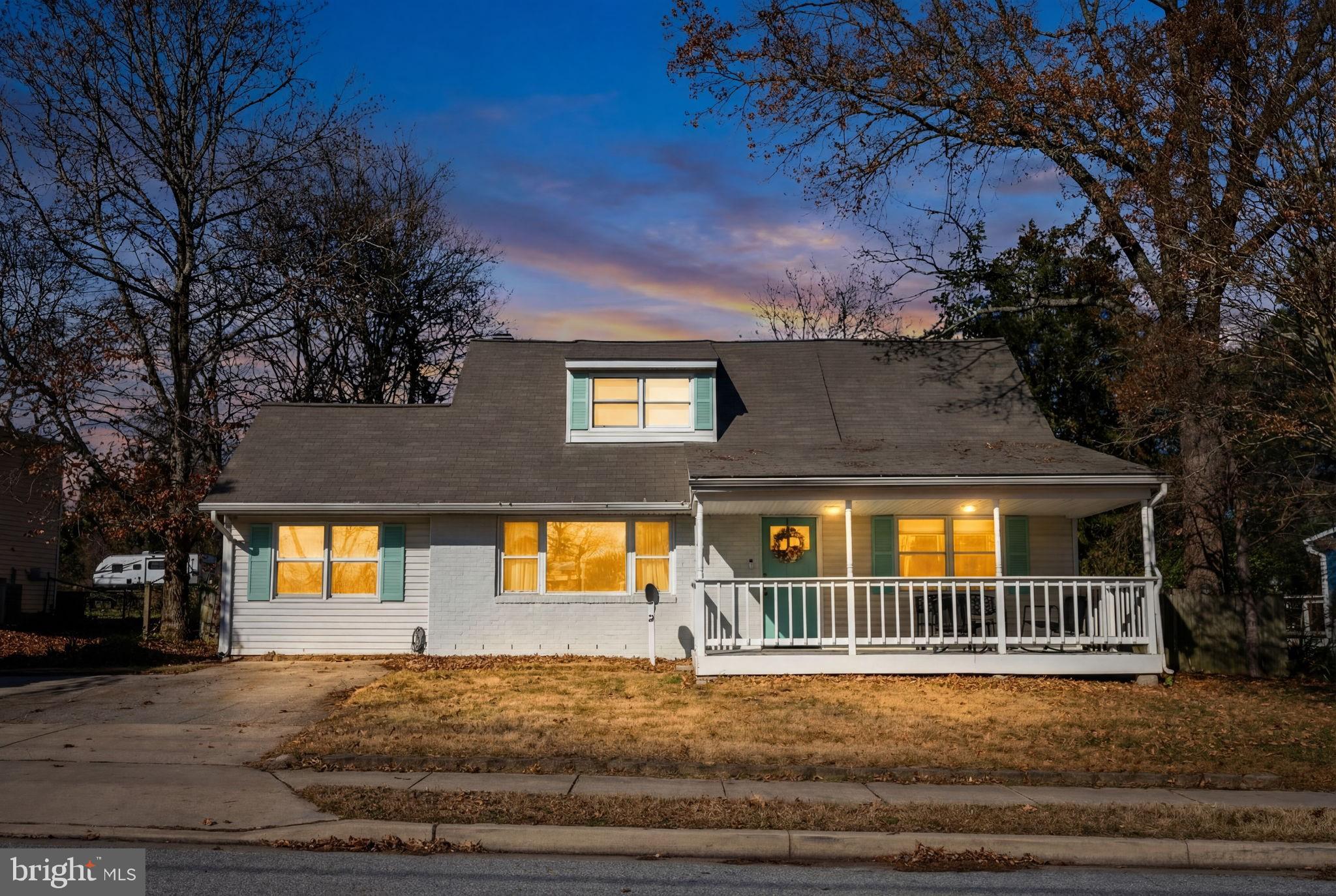 a view of a brick house with a yard plants and large tree