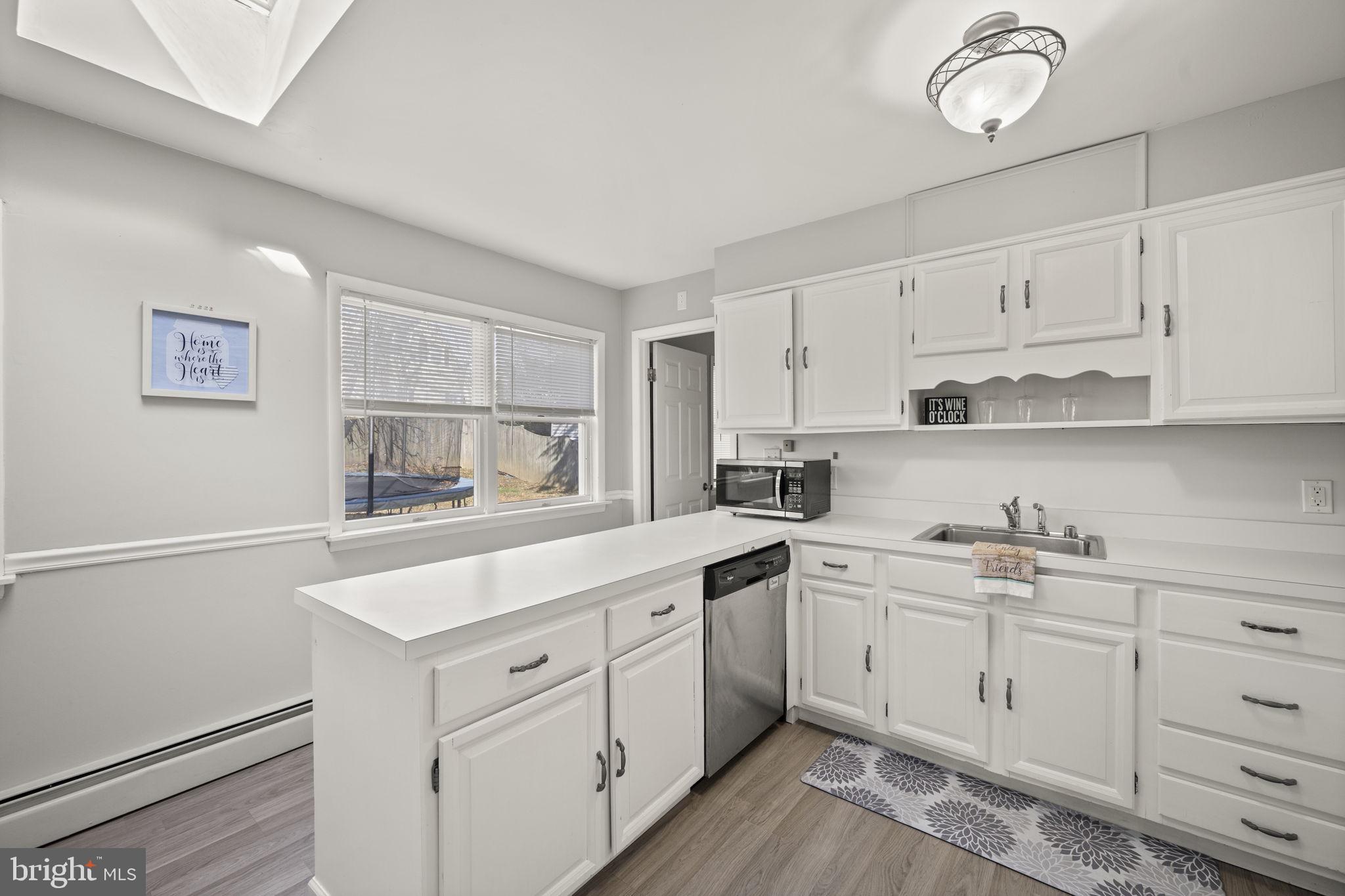 3 Leymar Road Glen Burnie, MD 21060 - Photo 19 of 60 a kitchen with a sink dishwasher a stove and white cabinets with wooden floor