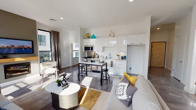 a living room with furniture a flat screen tv and kitchen view